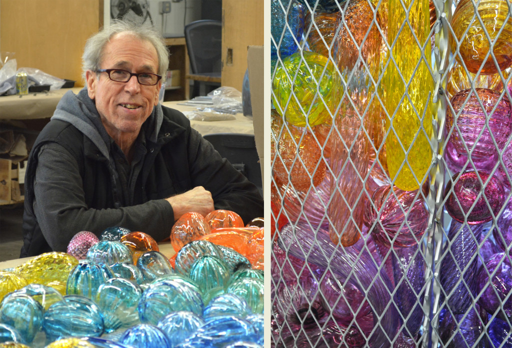 Jack Mackie posing with a handful of the week's glass orbs. At right is a close-up of the glass pieces layered inside one of the metal baskets that will adorn the installation.