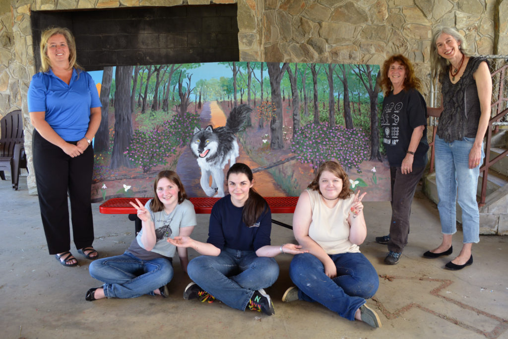 Students and others involved with the project pose with the completed wolf mural