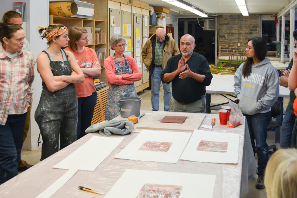 Artist Jaime Suarez giving a demonstration to a group of students on how to monoprint with clay and water