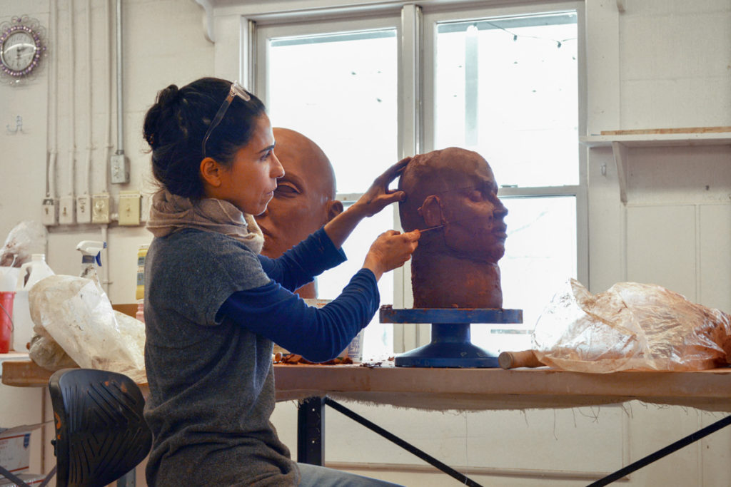 Cristina Cordova refines the features on the side of the clay head she is sculpting