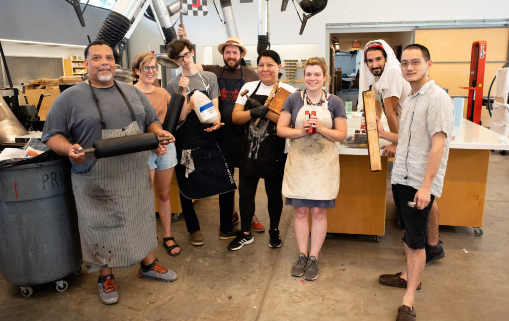 group photo of a printmaking class all holding up different tools