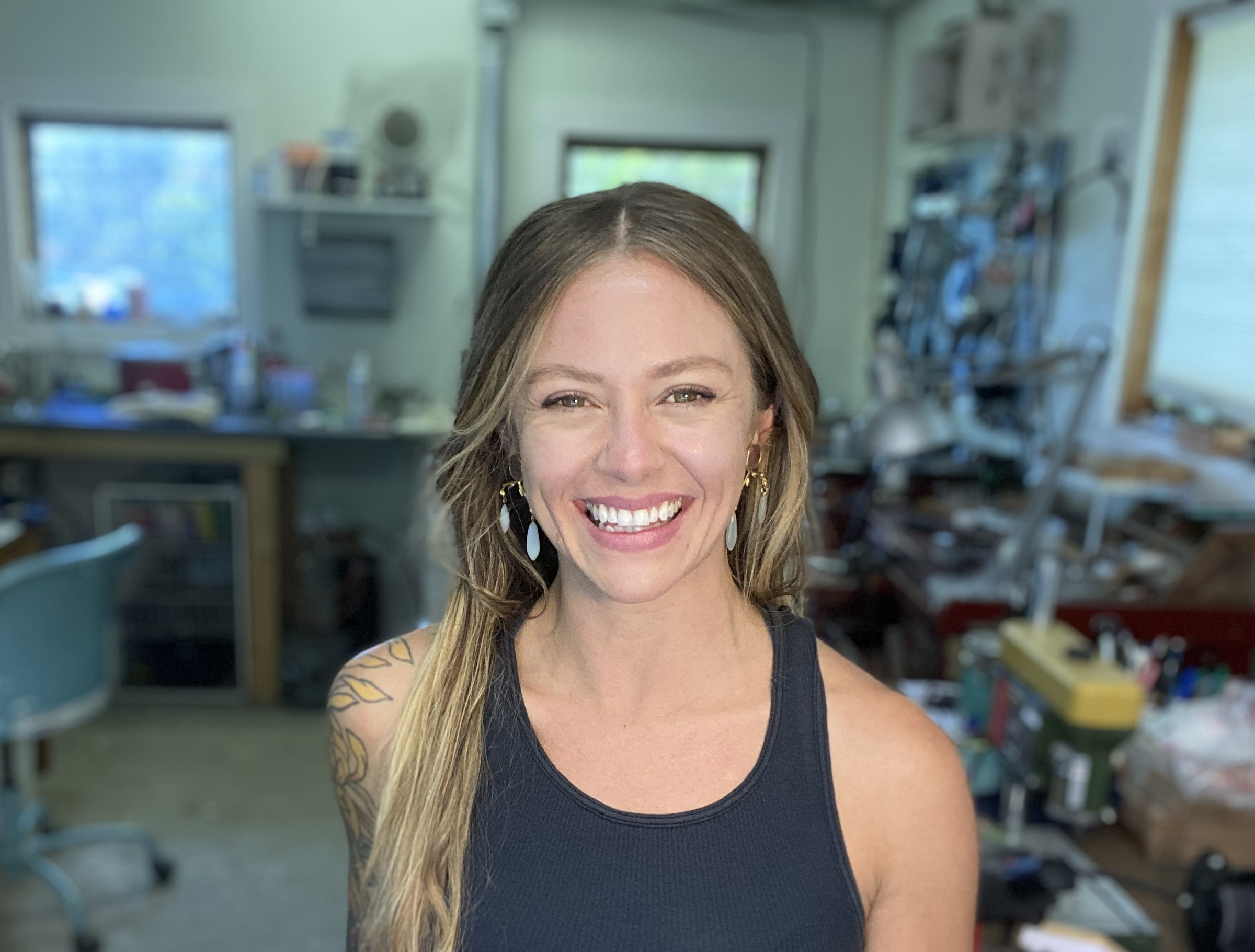 Photo of Anna Johnson in her studio. Anna is a young, white woman with long light brown hair and a big smile.