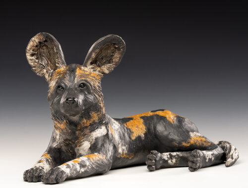 sculpture by Tina Curry, African Wild Dog, stoneware; raku fired with underglaze and clear crackle glaze, 9 x 14 inches