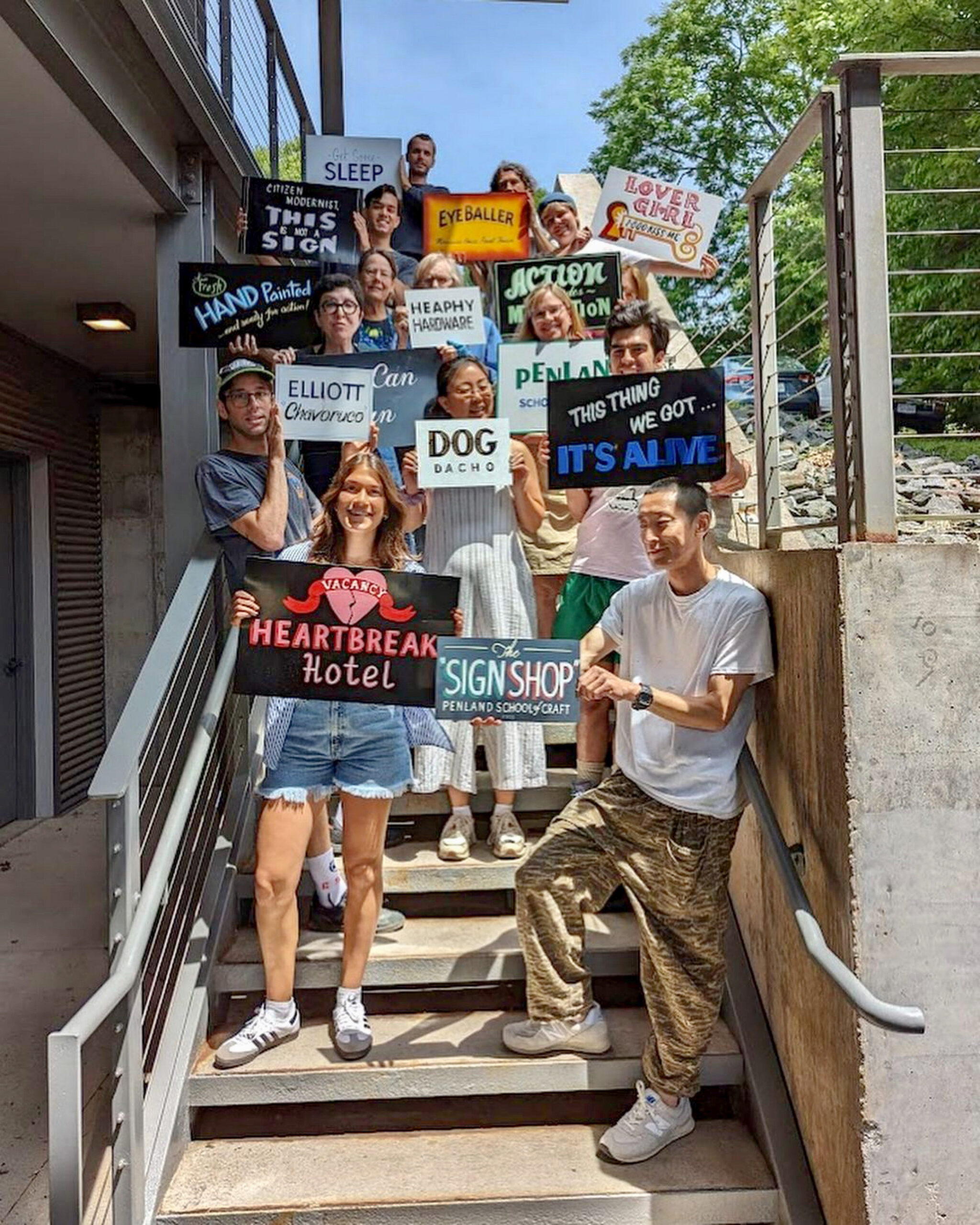 students pose with signs created in the drawing and painting studio