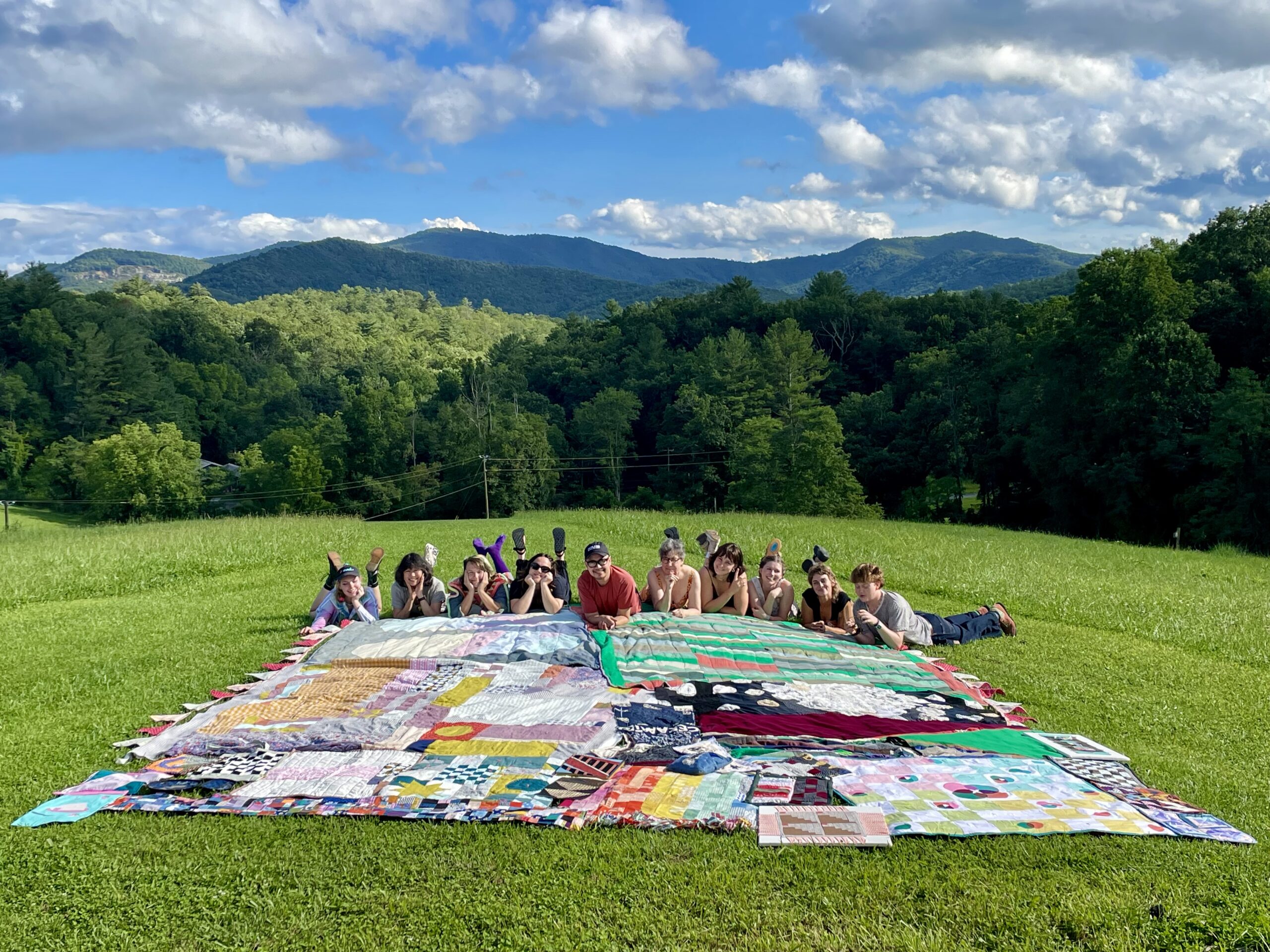 Students with quilting instructor, Pablo Arao display their quilts on The Penland Knoll